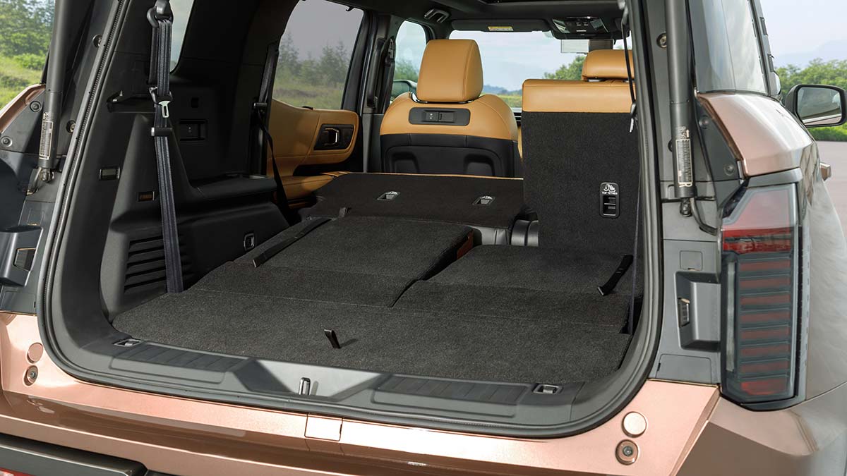 Cargo area inside bronze Mitsubishi Pajero SUV with third row and part of second row seats folded down.