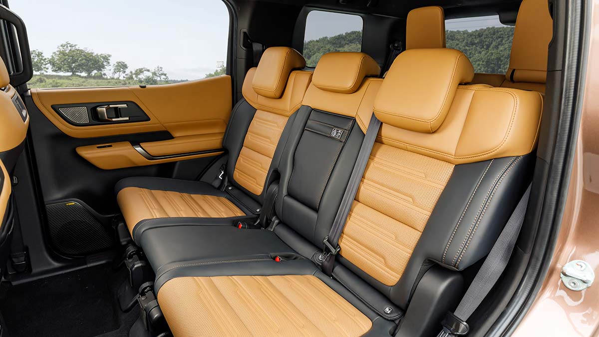 Second row in Mitsubishi Pajero 7-seater family SUV with black and tan upholstery on seats and doors.