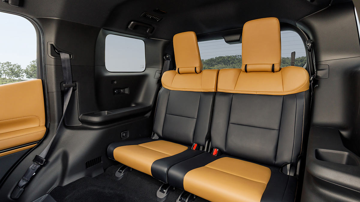 Third-row twin seats in Mitsubishi Pajero SUV with black and tan upholstery.