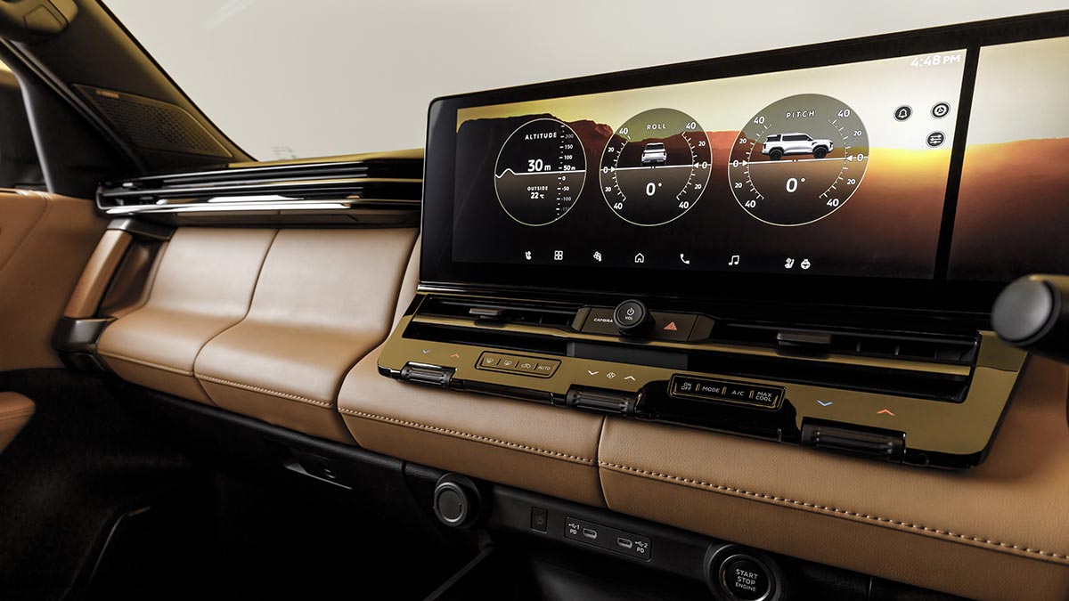 Twin 14.3-inch digital screen layout on tan-lined dashboard of Mitsubishi Pajero SUV showing off-road gauges.