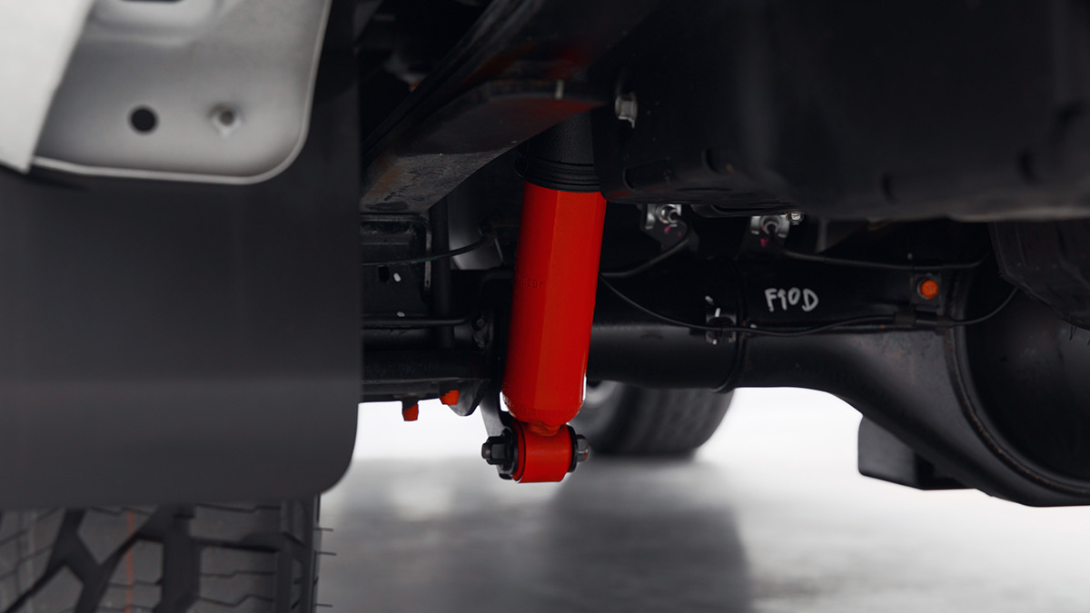 Bright red-coloured suspension component at rear axle of Mitsubishi Triton Raider ute.