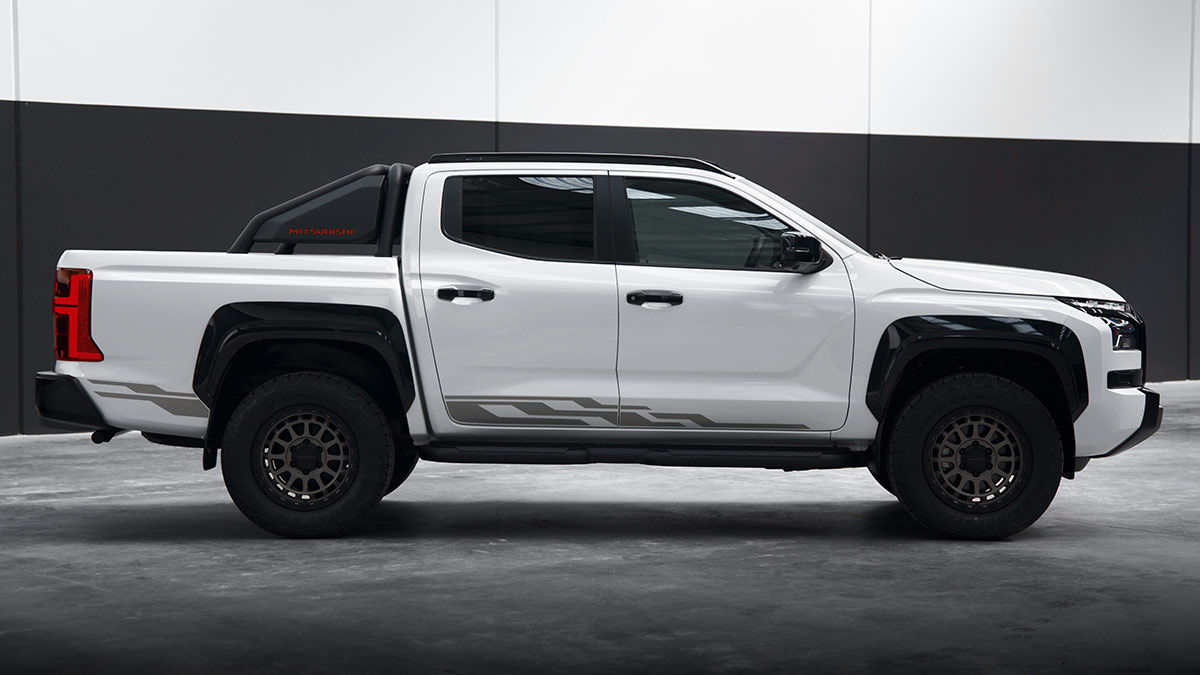Side view of white Mitsubishi Triton Raider dual-cab ute parked on polished concrete floor in empty warehouse.