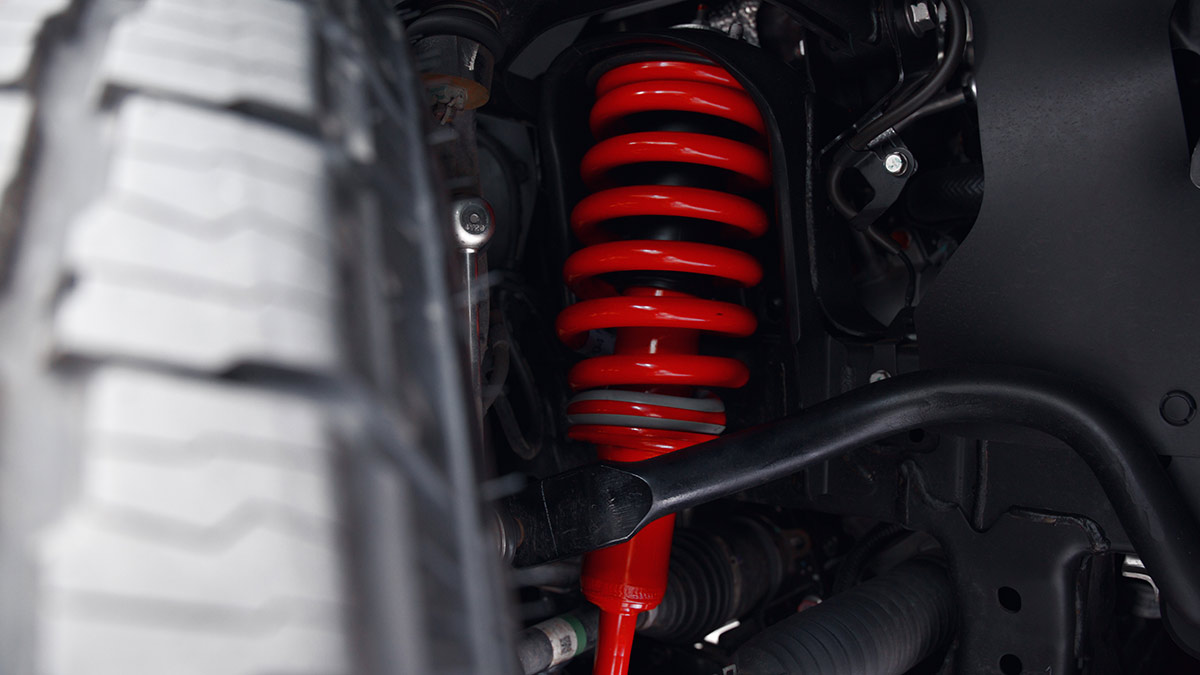 Bright red suspension components at front end of Mitsubishi Triton Raider ute.