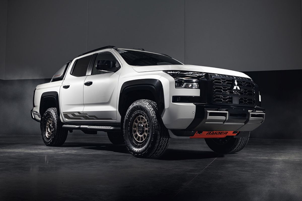 White Mitsubishi Triton Raider dual-cab ute parked on polished concrete floor in empty, dimly lit warehouse.