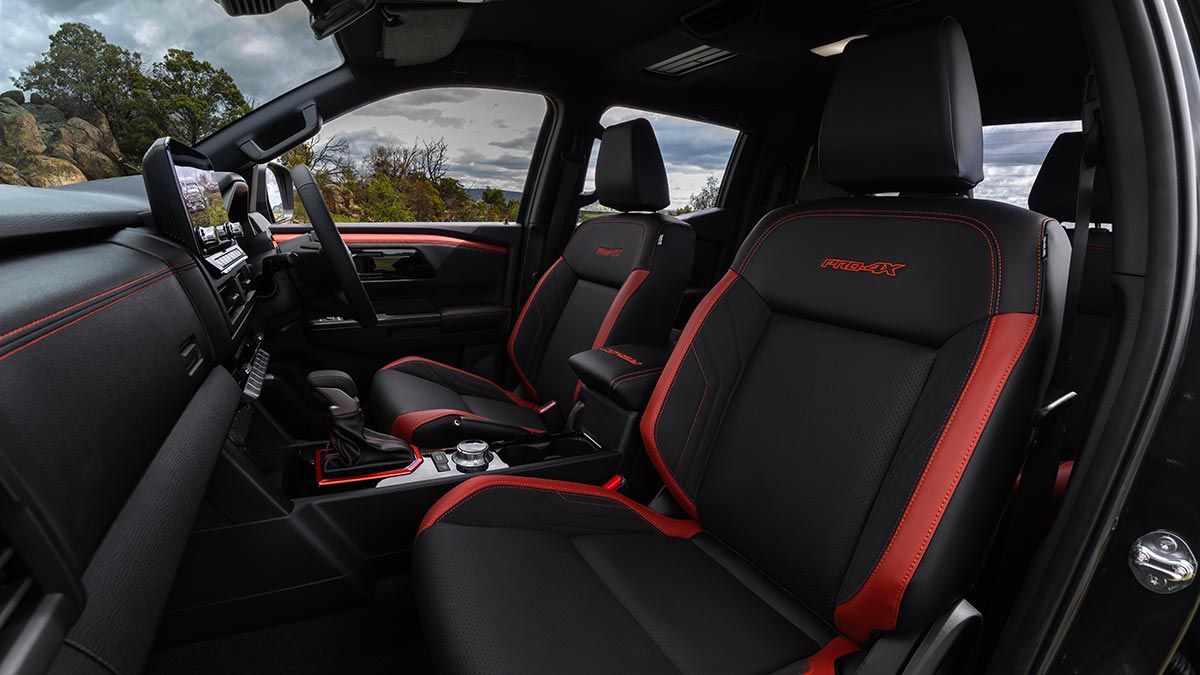 Front seat area of Nissan Navara Pro-4X with bright red trim highlights on seats, console, dash and doors.