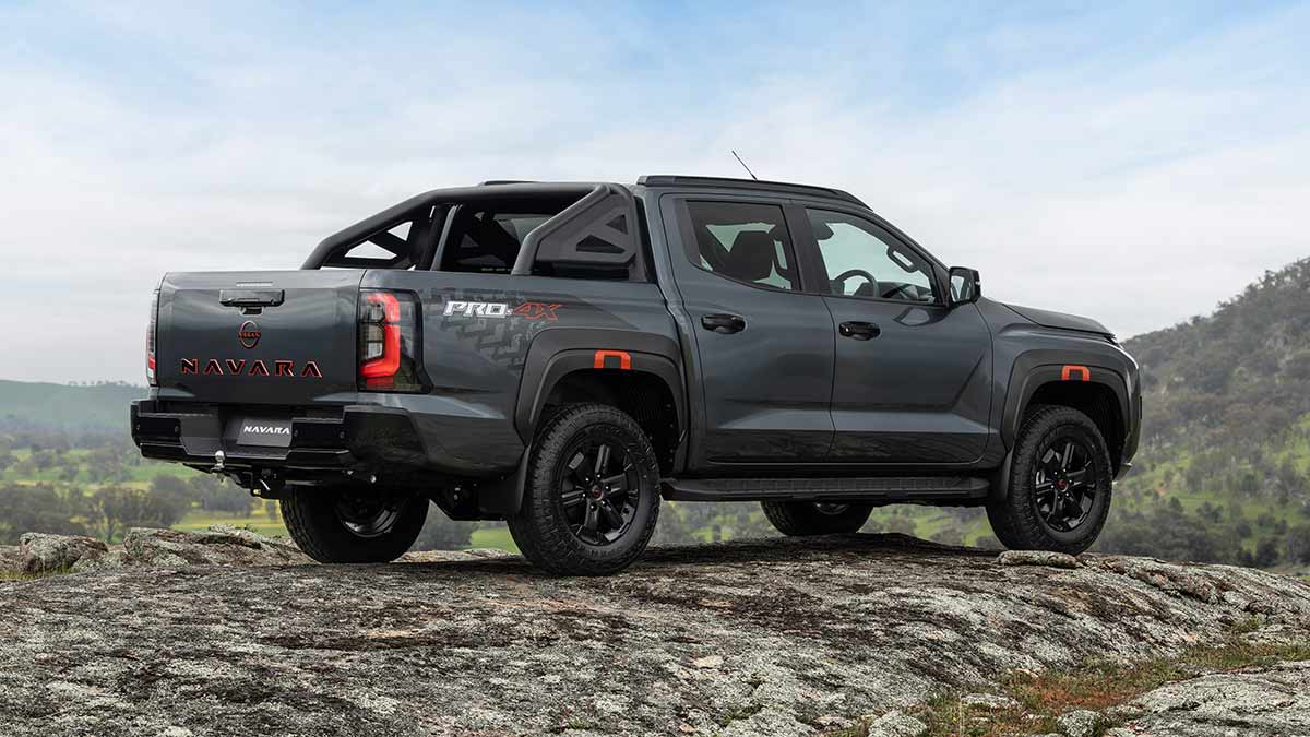 Rear view of dark grey Nissan Navara Pro-4X on rocky granite hilltop with lush green pastoral land, bush and ranges behind.