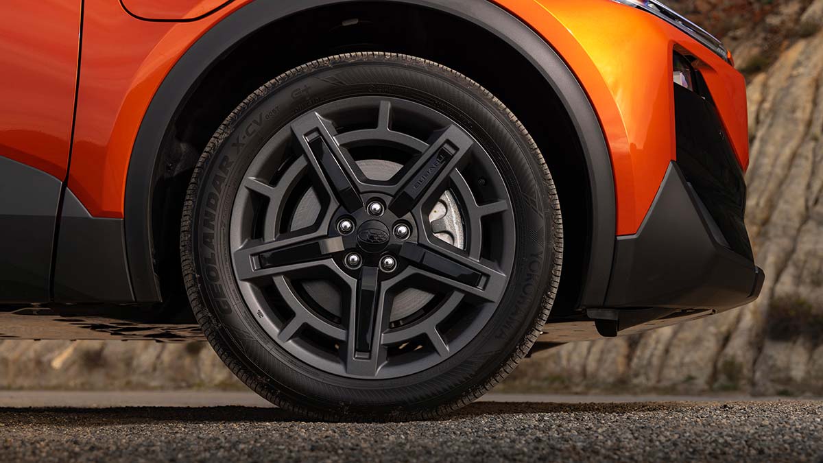 Black alloy wheel with star-shaped design on orange metallic Subaru Uncharted small SUV.
