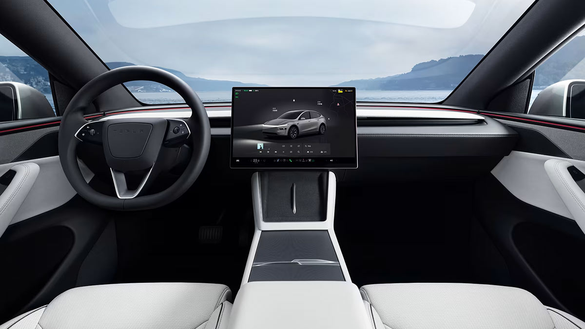 Minimalist cockpit of Tesla Model Y L SUV with large central screen, few controls and white cabin trim.