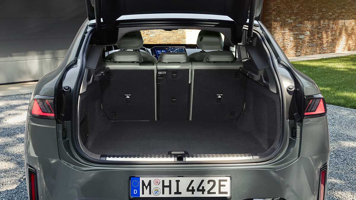 Tailgate open on metallic sage green BMW iX4 50 xDrive coupe-style SUV showing cargo area with 60/20/40 split-fold rear seats.