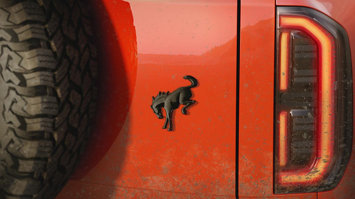 Detail shot of Bronco horse badge and spare tyre mounted onto red Ford Bronco Basecamp SUV.