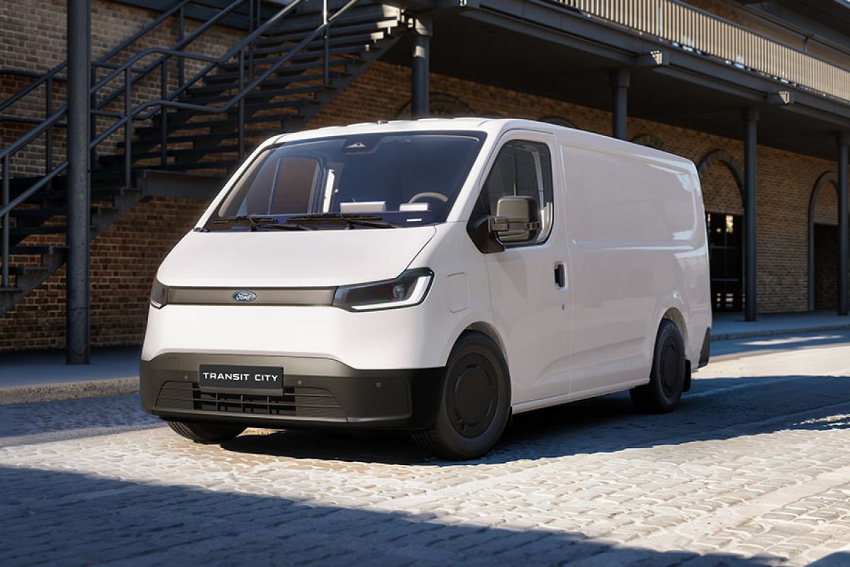 White European-spec Ford Transit City electric van parked on brick-paved forecourt of double-storey heritage industrial building.