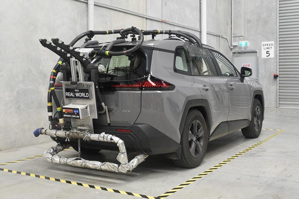 Rear view of grey metallic Toyota RAV4 rigged up with fuel economy and emissions testing equipment in warehouse, ready for real-world testing. 