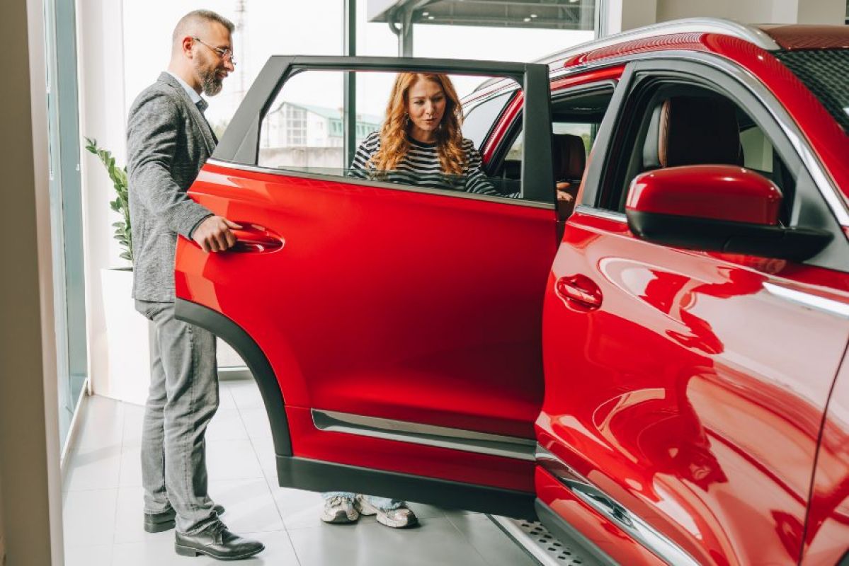 car salesman showing a female buyer a red car