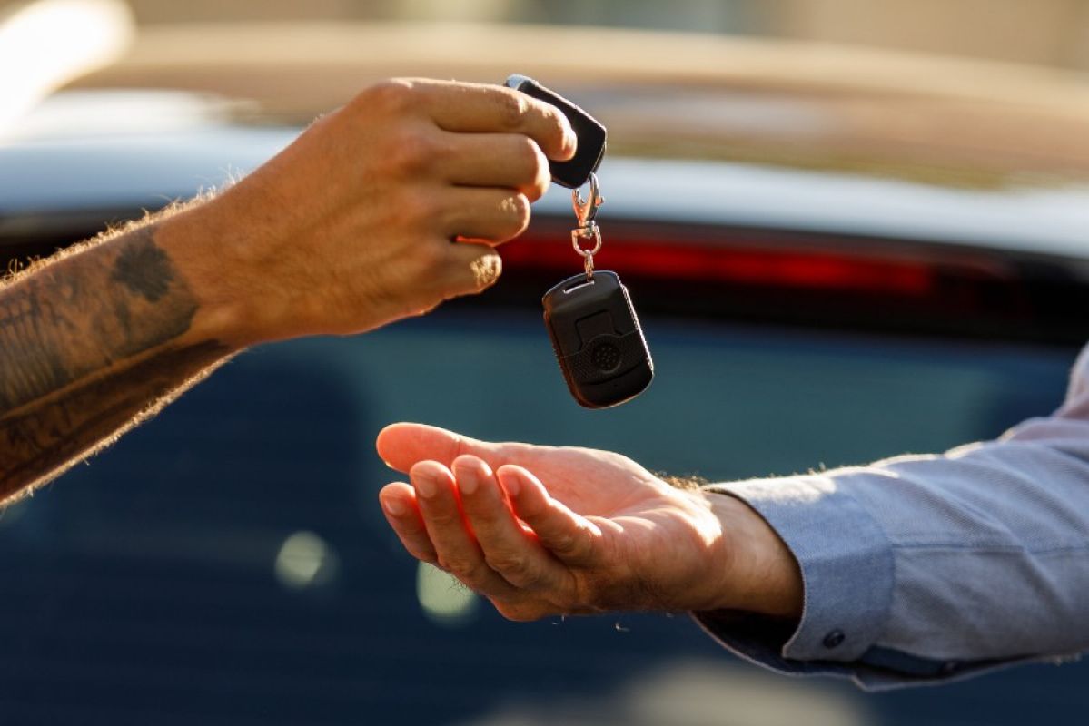 A person handing a pair of car keys to another person