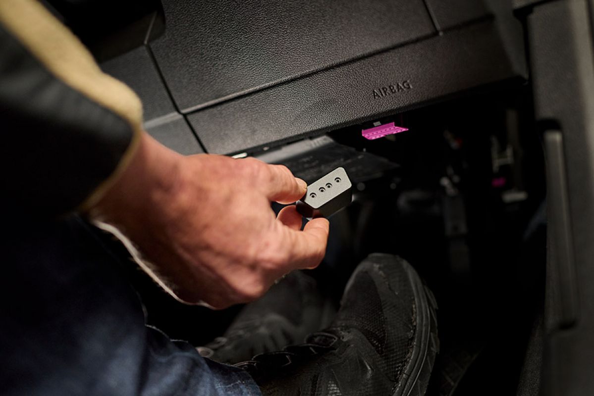 person pushing start button in car