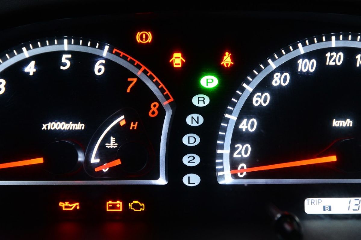 A car dashboard lit up at night and showing warning lights for several functions