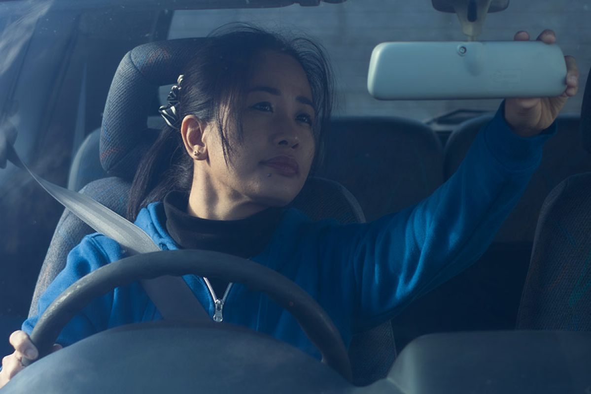 Woman adjusting rear-view mirror to back car