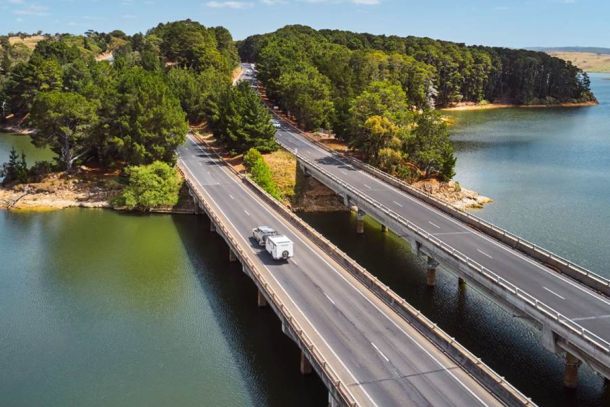 car towing caravan on a highway bridge in summer