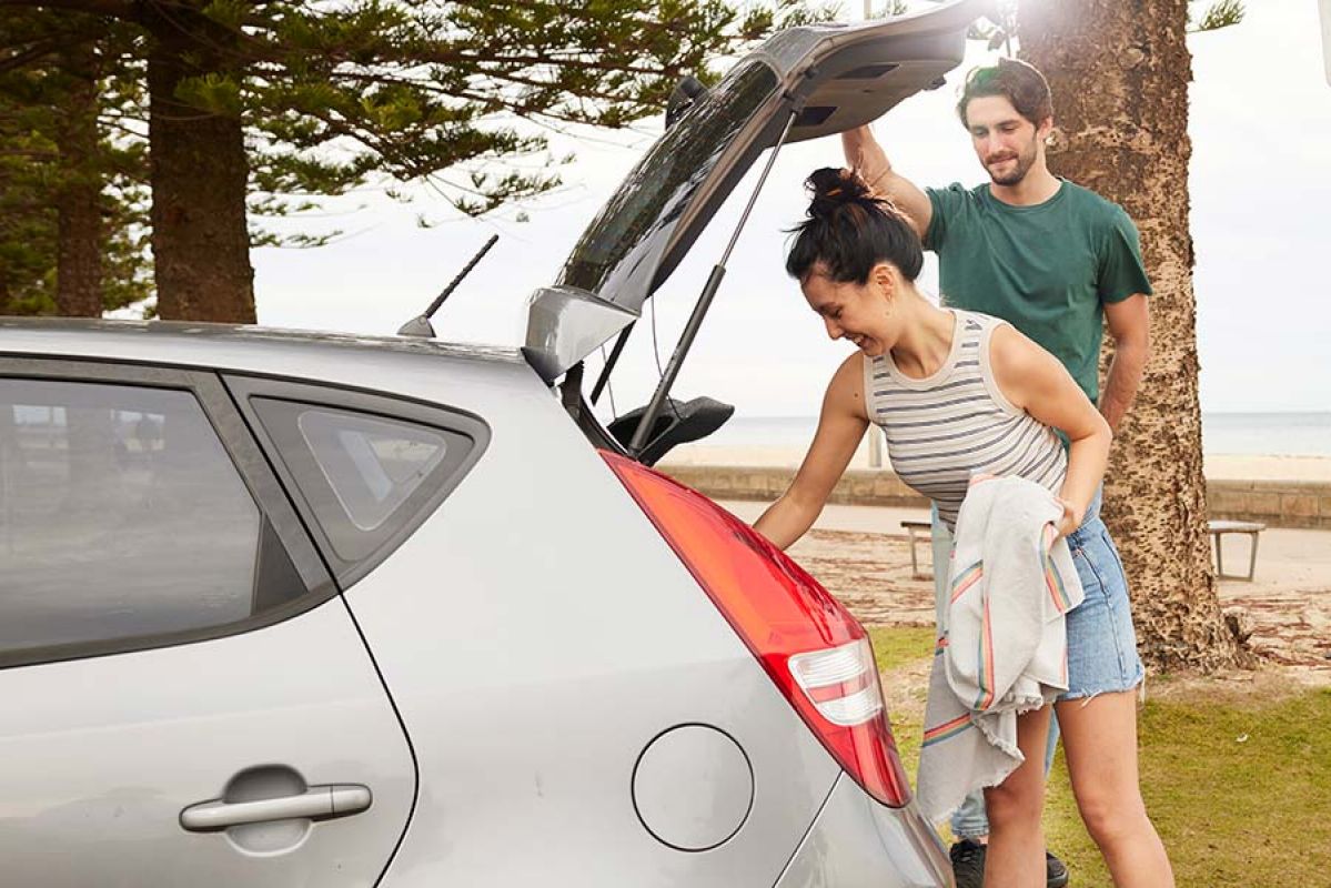 a couple get things out of their boot at the beach.