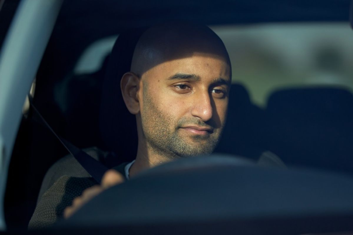 A tired-looking man with heavy eyes driving a car