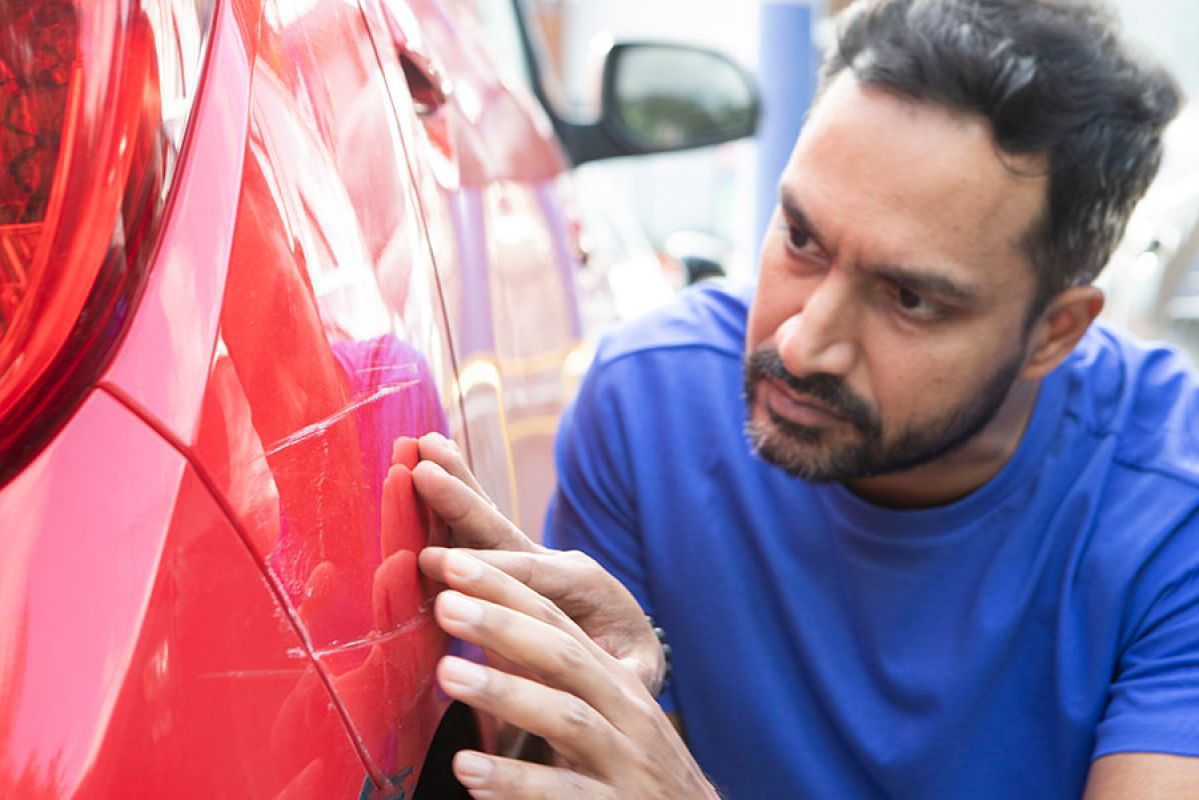 Prominent white scratches on body of red car near tail light