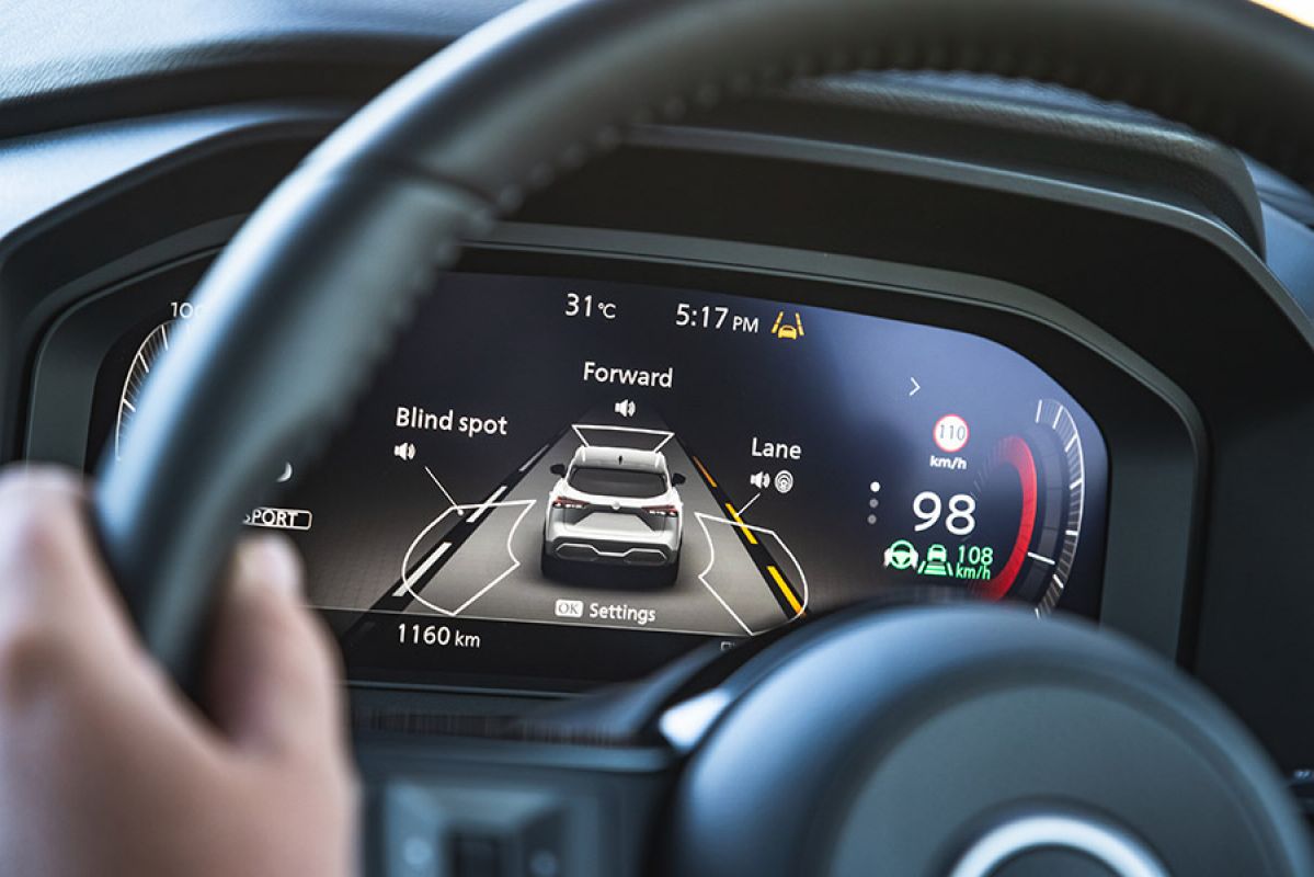 Instrument panel of the Nissan Qashqai e-Power SUV showing graphic of car with safety systems for lane keeping, forward camera view and blind spot monitoring