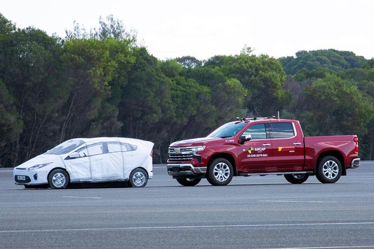 Large red Chevrolet Silverado pick-up truck close behind much smaller white passenger car in ANCAP safety test.