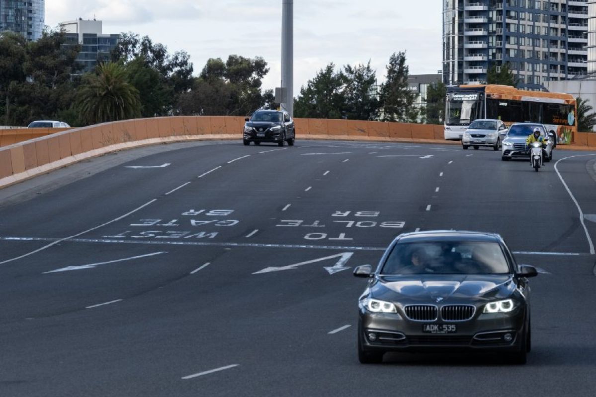 Cars driving along a four-lane road in Melbourne. Line markings and arrows are clearly visible