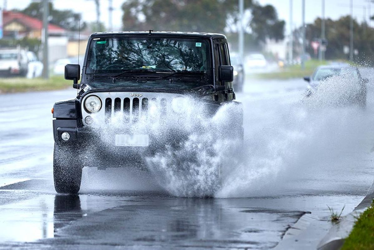 jeep driving on flooded road causing wave of water from tyre