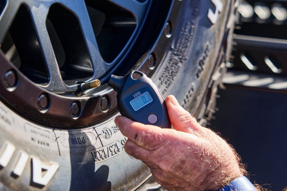 A persons using a digital tyre gauge to check tyre pressure