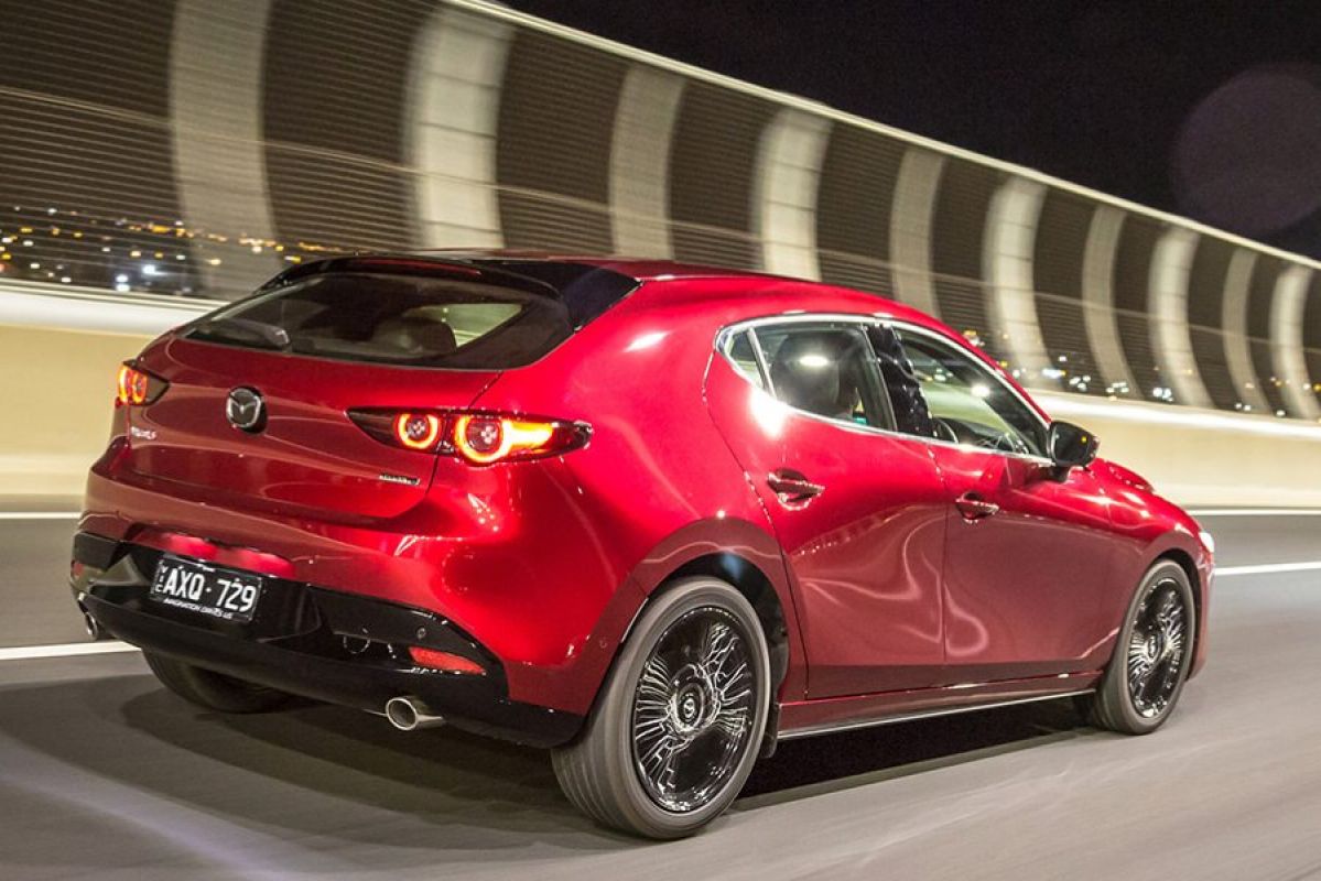 A red 2019 Mazda  3 driving over the Westgate Bridge at nighttime