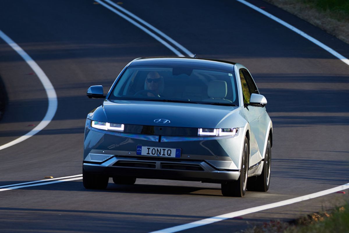 Frontal shot of blue Hyundai Ioniq 5 electric car on downhill corner of country road