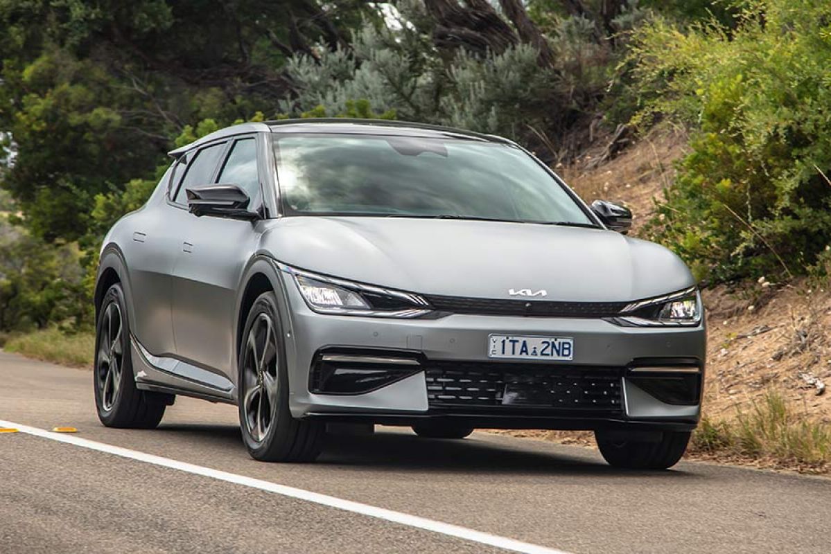 Metallic grey 2022 Kia EV6 SUV on winding Victorian coastal road with high sandy banks and tea trees.