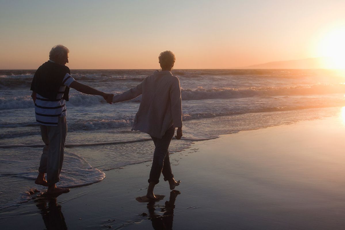 father and daughter sitting on beach with surfboards looking out to sea