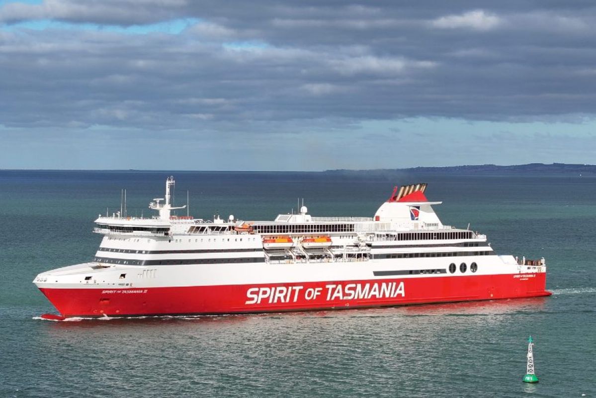 Spirit of Tasmania sailing on steely blue-green waters. A green buoy can be seen in the foreground while land can be seen in the distant background