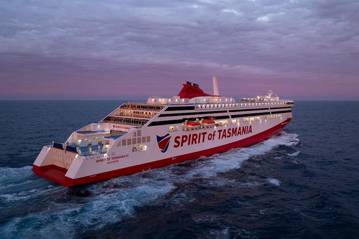 Spirit of Tasmania sailing on steely blue-green waters. A green buoy can be seen in the foreground while land can be seen in the distant background