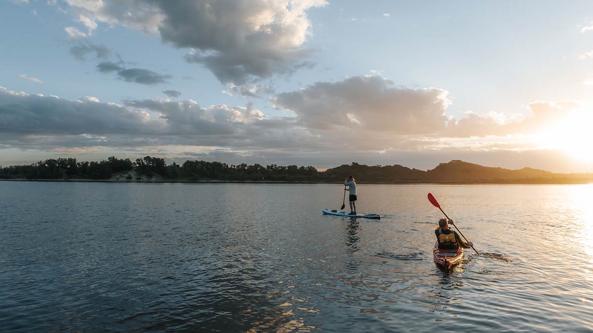 Kayaker and paddle boarder on water at Marlo at sunset
