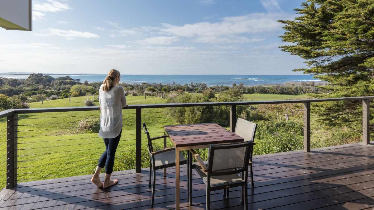 woman standing on balcony looking at the sea