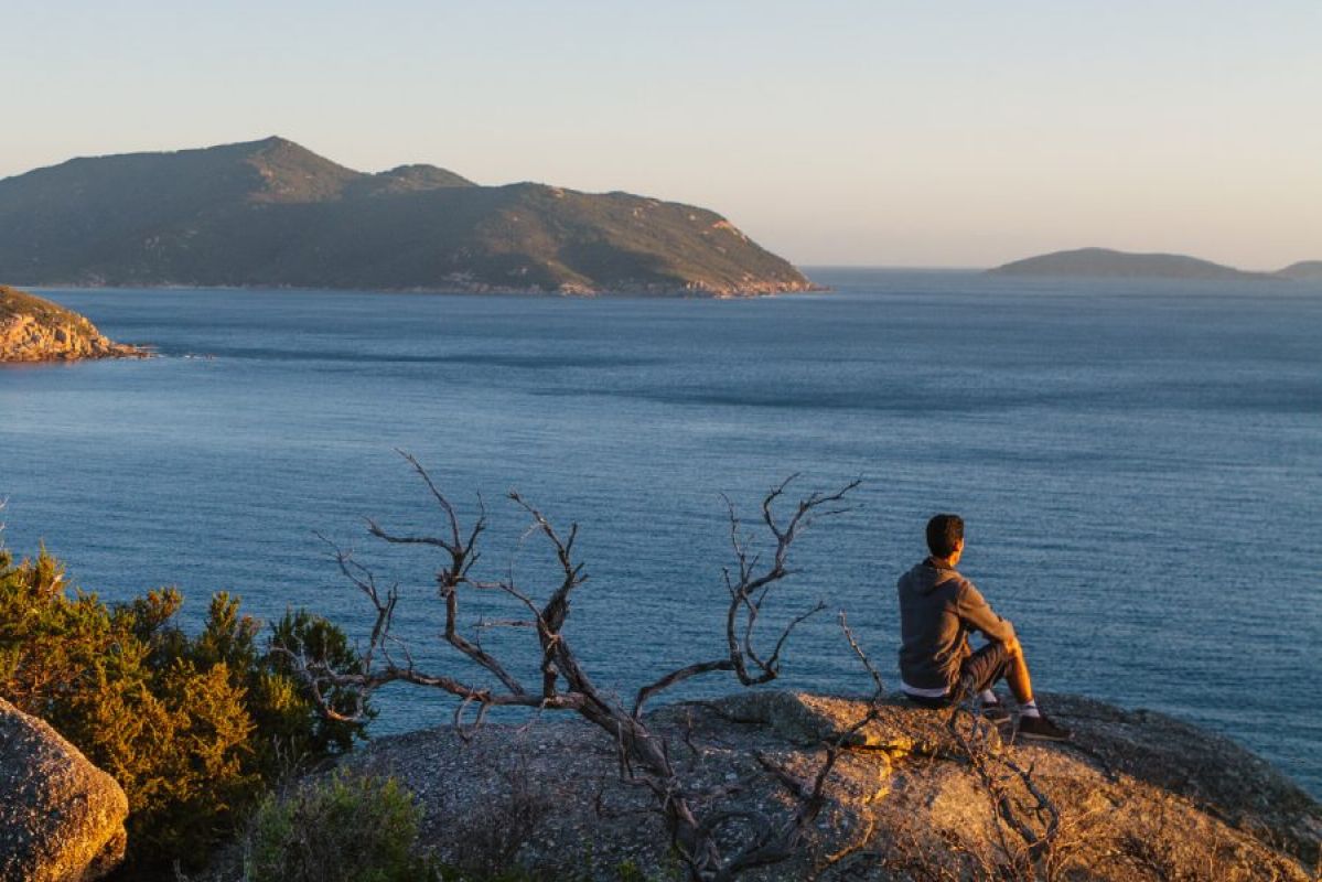 young man sitting on a rock looking over the ocean