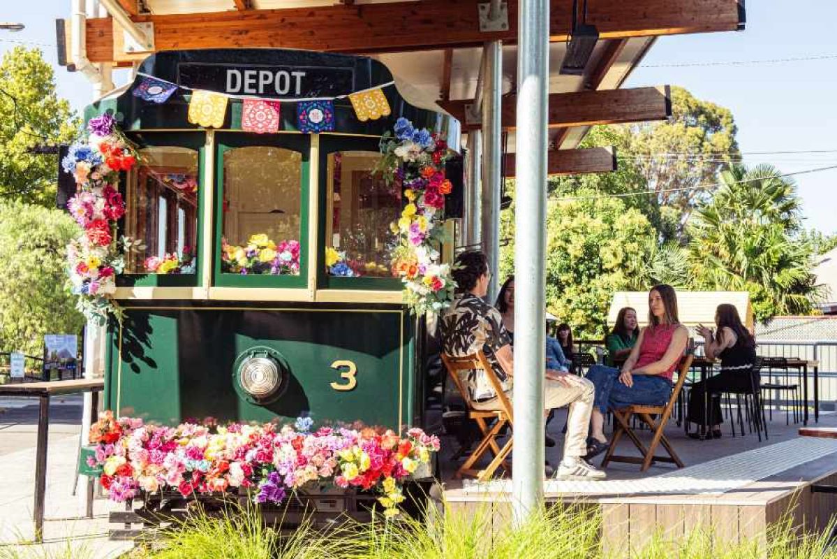 people sitting on a deck by a tram covered in flowers