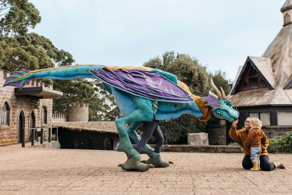 mother and child kneeling and patting a dragon in a medieval castle