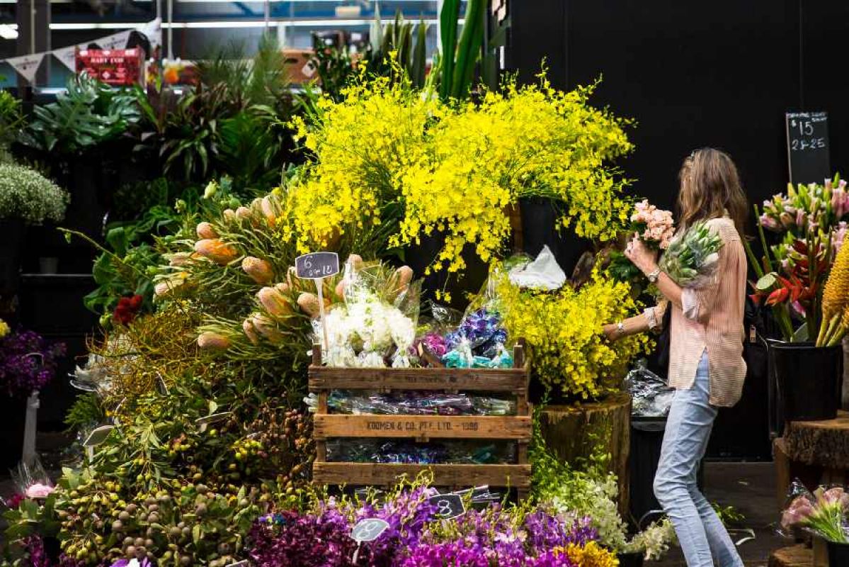 A woman choosing flowers from an overflowing stall at Prahran Market