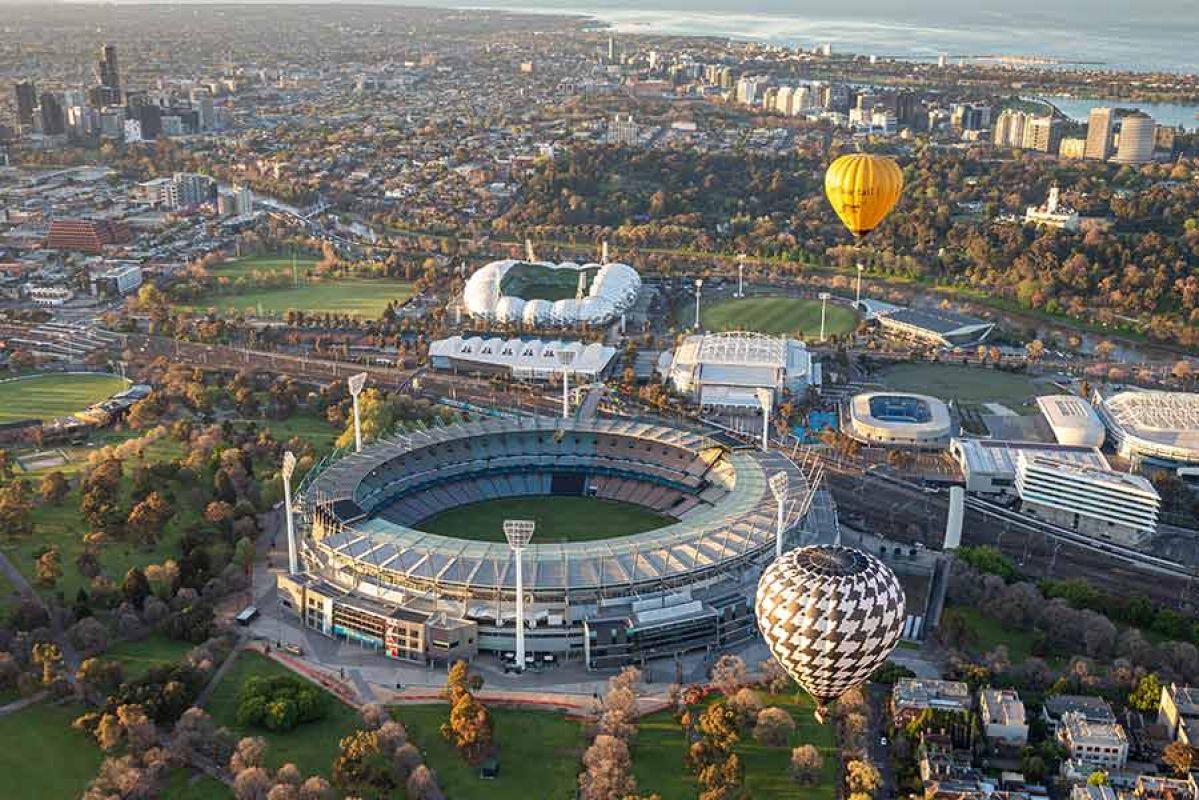 Aerial view of MCG and other sporting venues with hot air balloons.