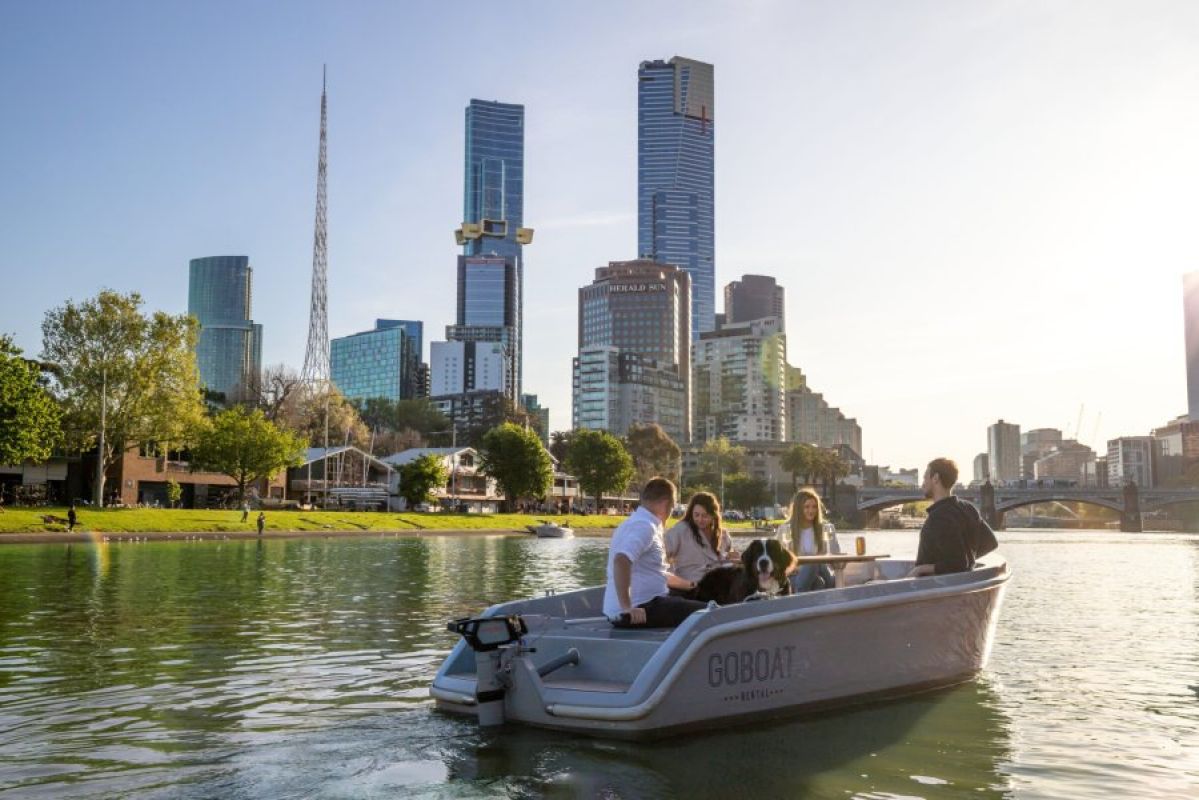 four friends and their dog on a hire board on the Yarra River in Melbourne with city skyline behind