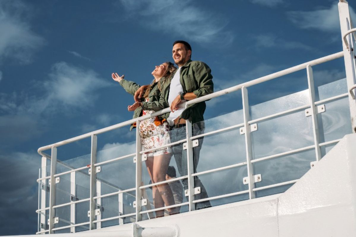 man and pregnant woman on upper level of cruise ship smiling