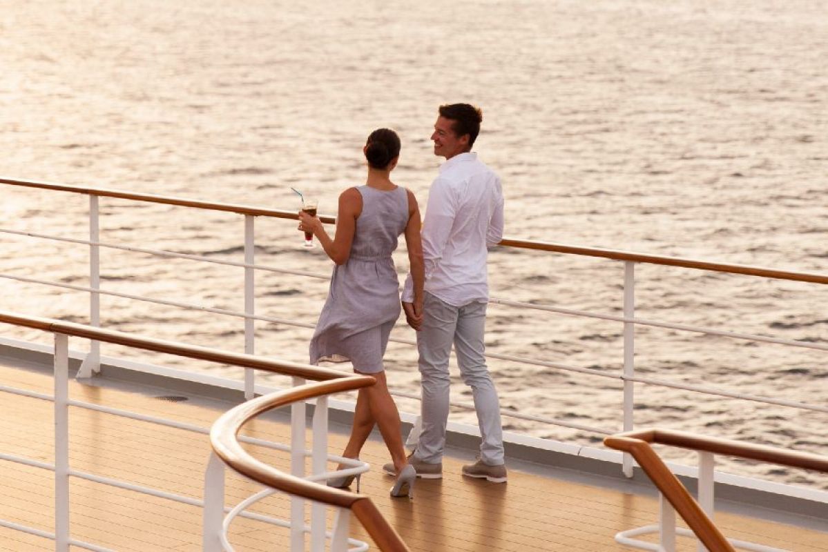 man and woman holding hands and walking on cruise ship