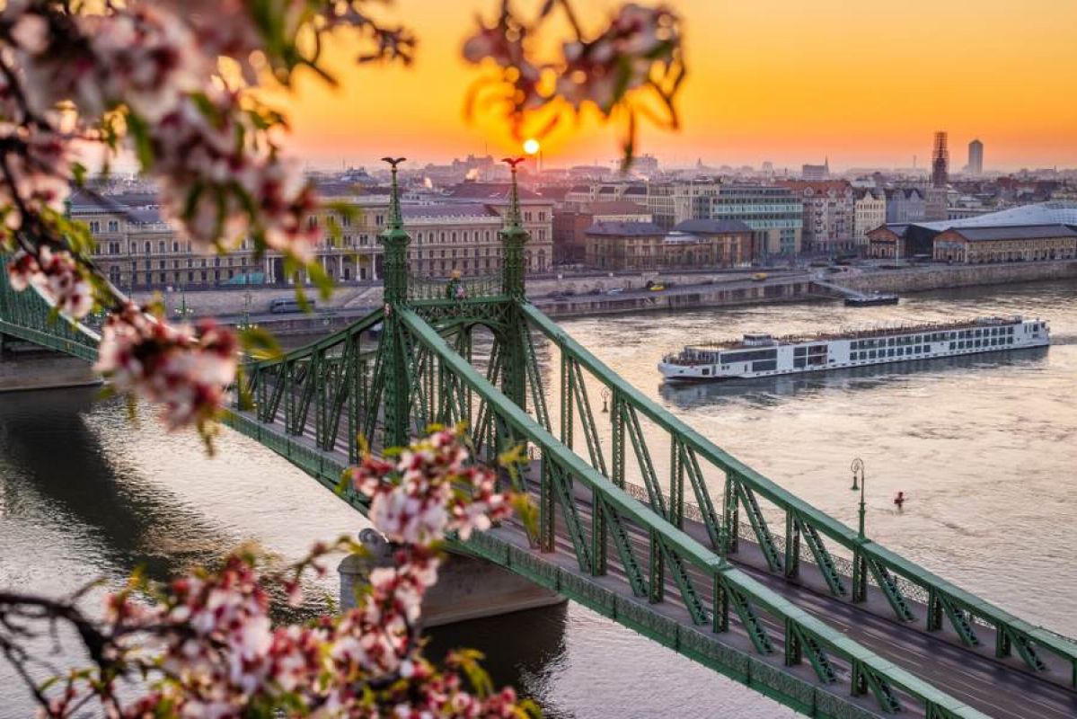 cruise ship on European river passing under bridge
