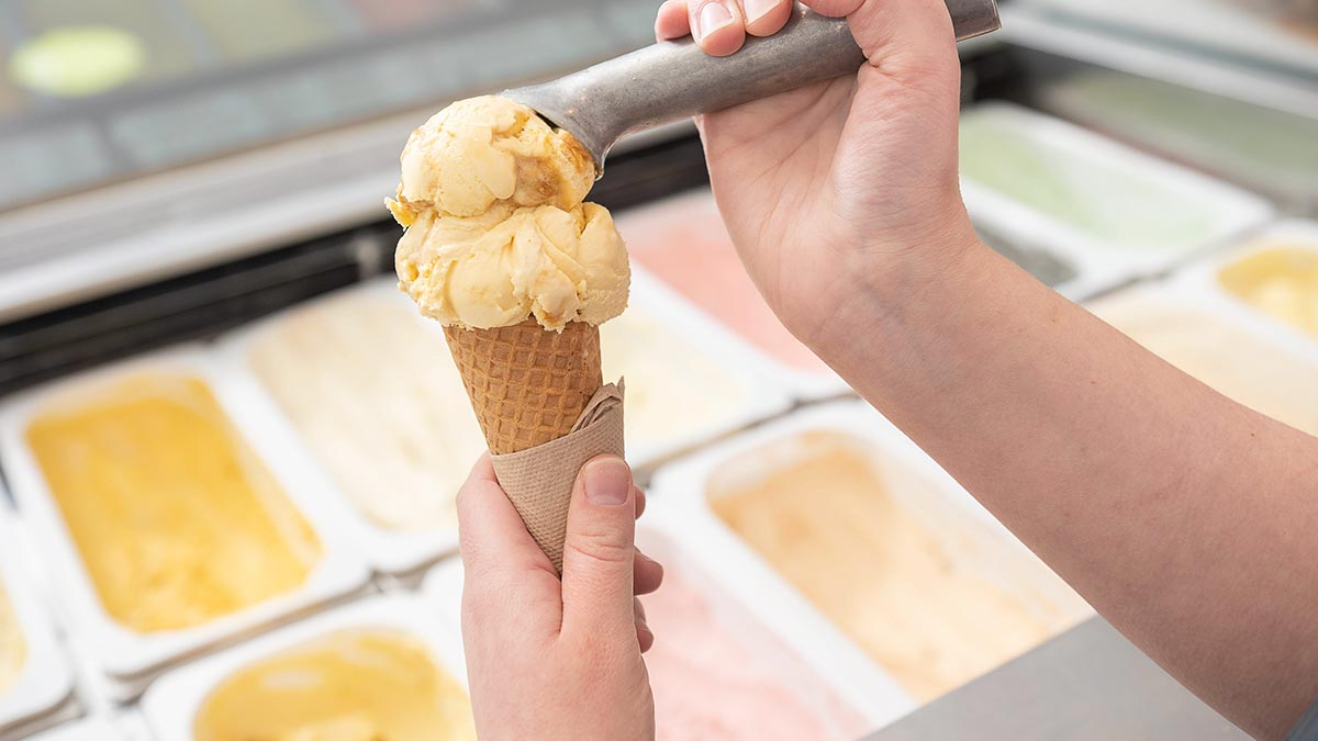 person scooping ice cream into a cone