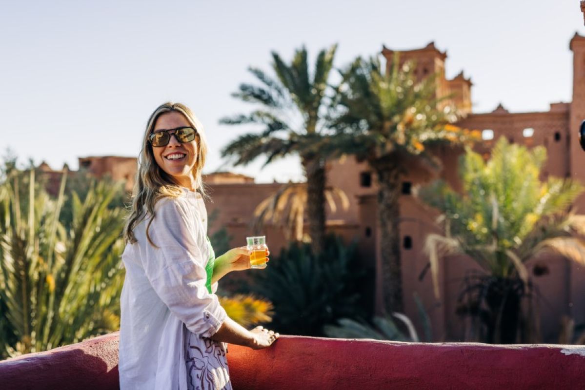 young woman holding a drink on balcony overlooking Morocco