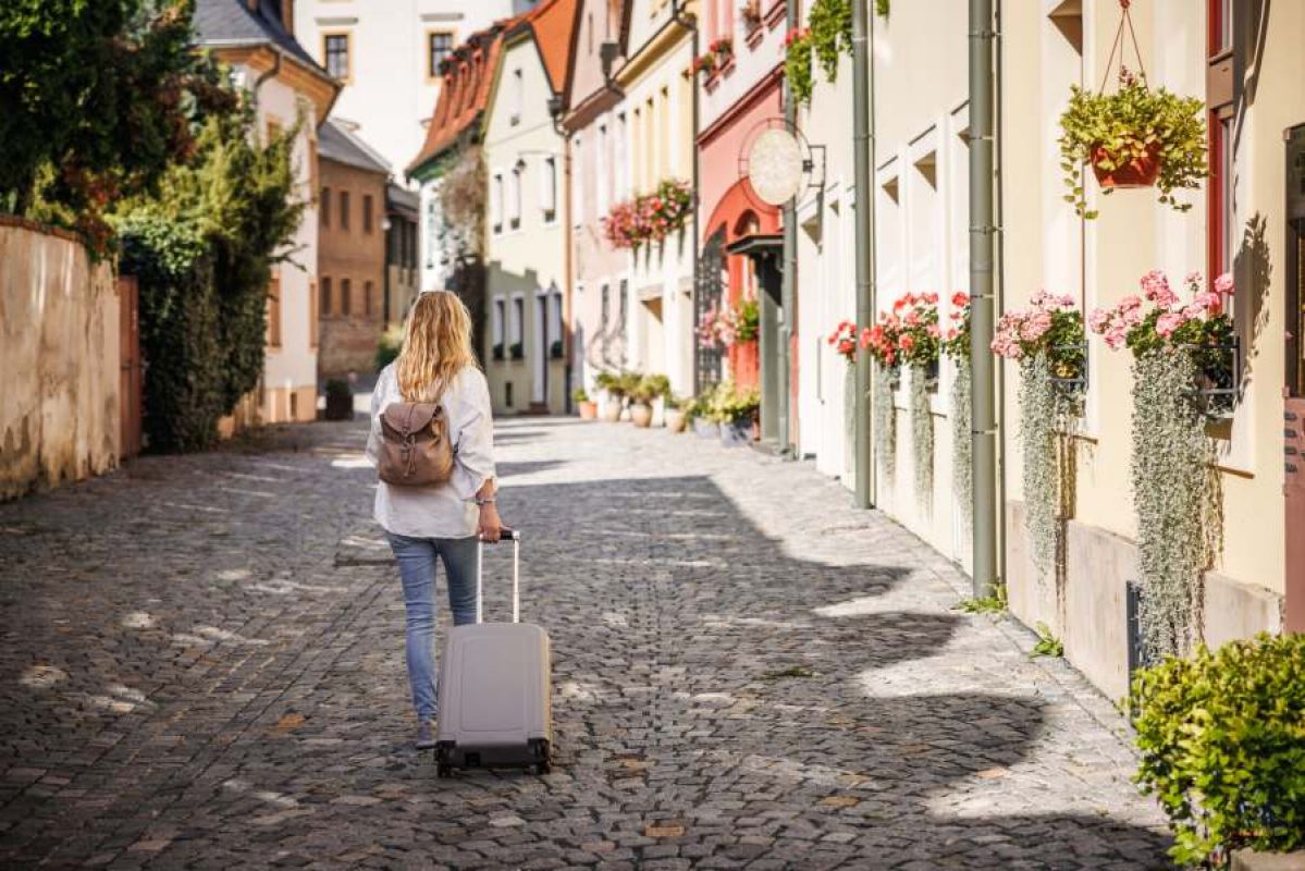 woman wearing backpack and taking suitcase up a cobbled street in Czechia